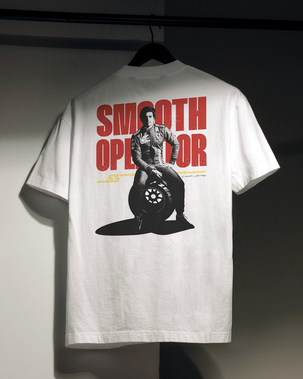 White t-shirt with graphic design and text on a hanger against a dark background